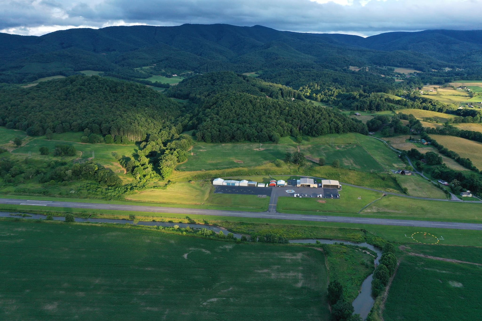 Aerial view of Johnson County Airport runway and hangars among green mountains
